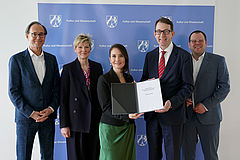 Foto zeigt 5 Personen bei der Übergabe des Berichts.